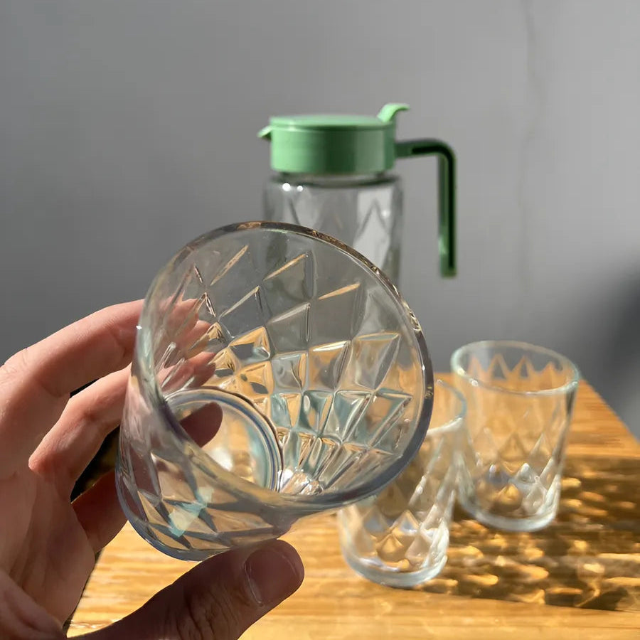 Clear glass with a green lid on a wooden surface